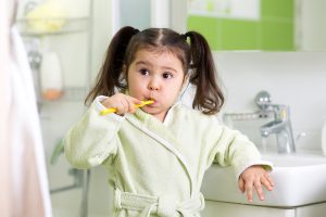 Child little girl brushing teeth in bath