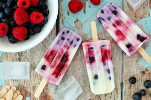 Group of homemade mixed berry yogurt popsicles on a rustic wood background