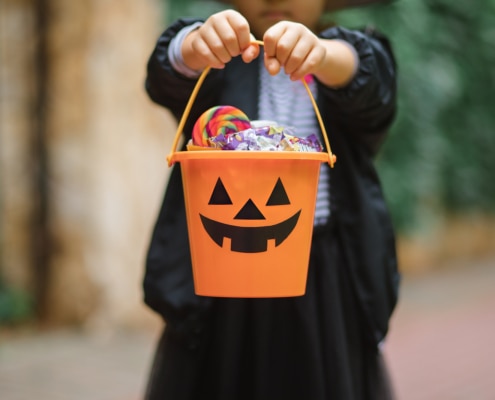 Little Cute Girl In Witch Costume Holding Jack o lantern Pumpkin